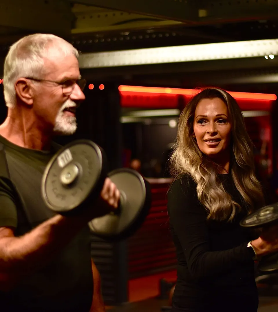 Trainer van ClubFit begeleidt een lid tijdens een krachttraining met dumbbells in de sportschool in Enschede